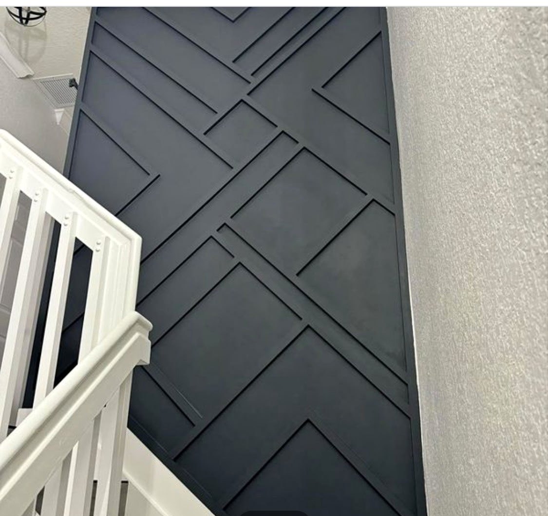 Finished dark geometric feature wall beside a staircase with white railings