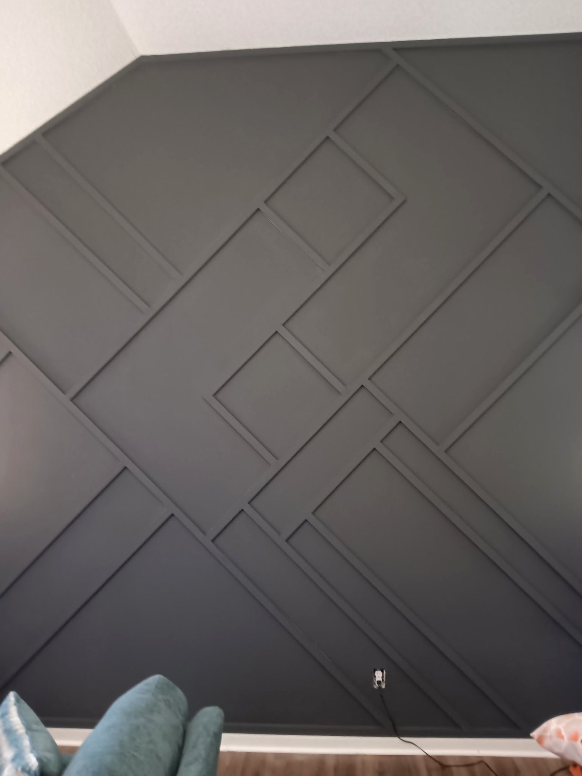 A finished dark accent wall with a geometric wood panel design