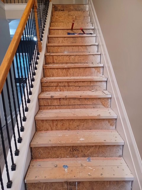A staircase with bare unfinished subfloor treads before the build
