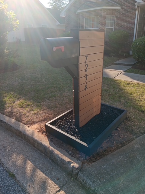 New custom wooden mailbox post with horizontal slats, a black mailbox, and a raised planter base