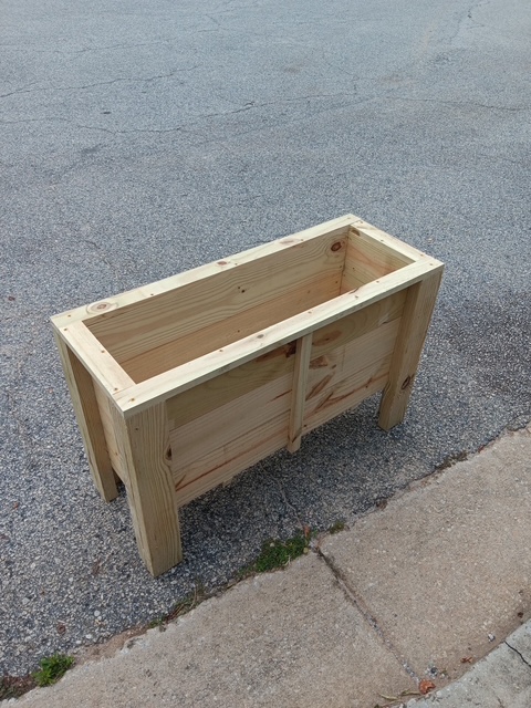 Raised wooden planter box built from natural, unfinished wood