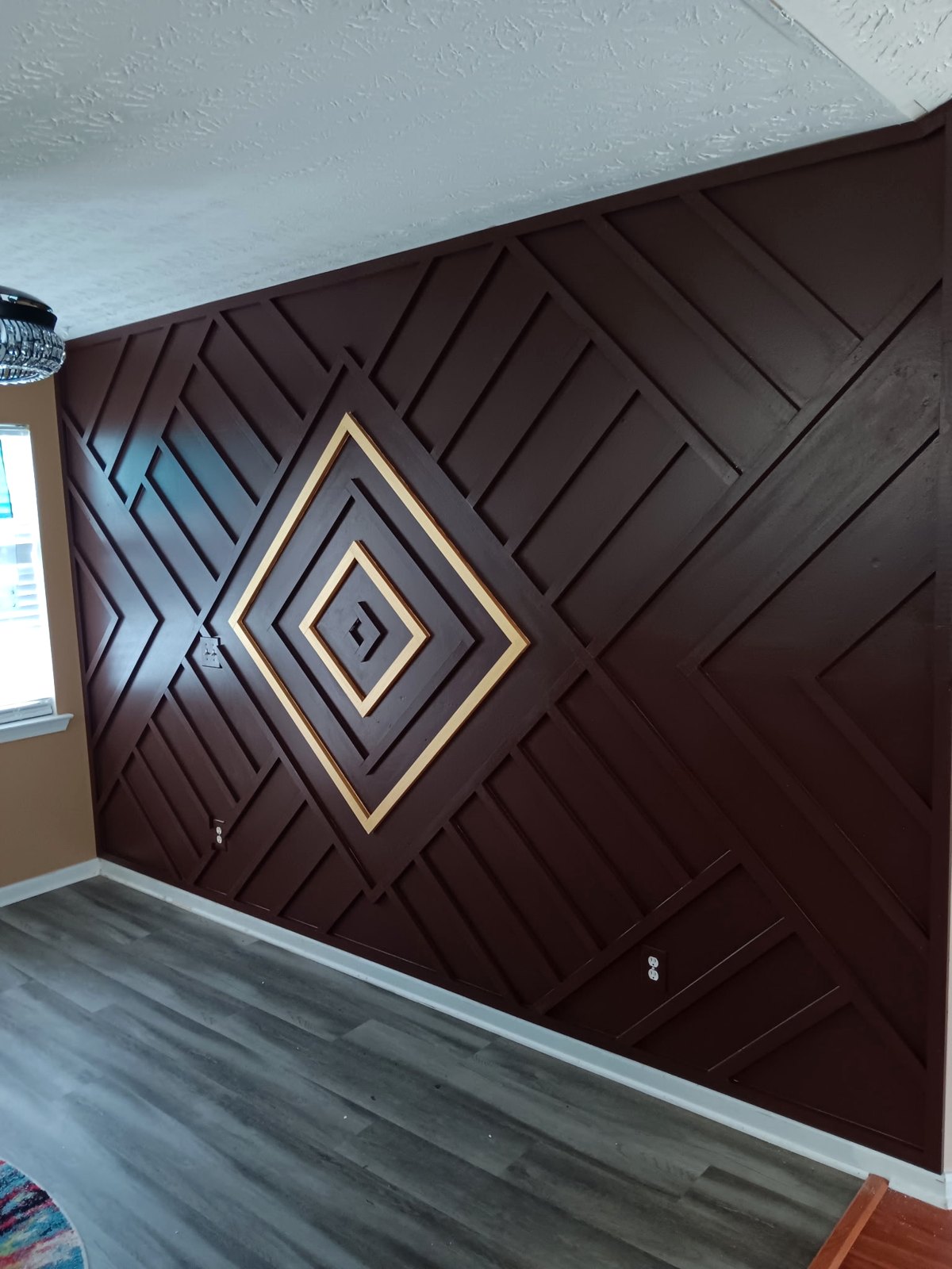 A dark brown geometric paneled feature wall with a gold diamond inlay at its center