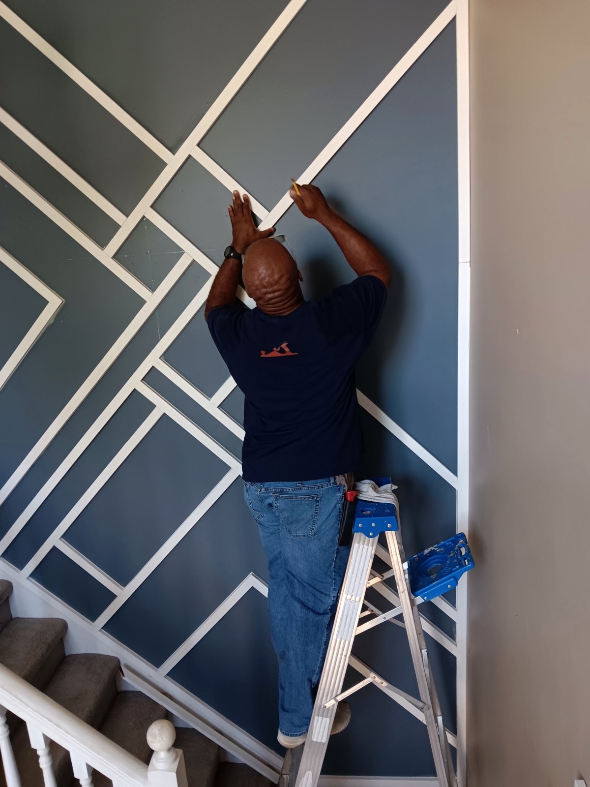 Wood trim being fitted on a staircase wall during the feature wall project