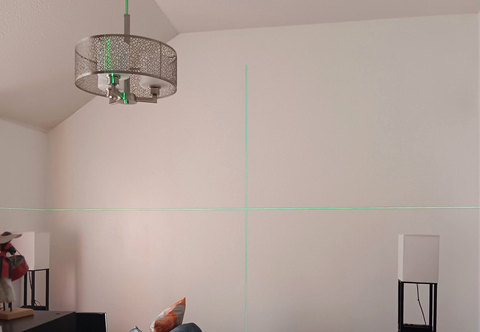 A plain wall marked out with a green laser level before the wall feature project